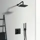 Schwarzes Duschsystem an einer hellen Wand, bestehend aus einer Kopfbrause, einem Handbrause-Element und einem Thermostat von Ideal Standard.